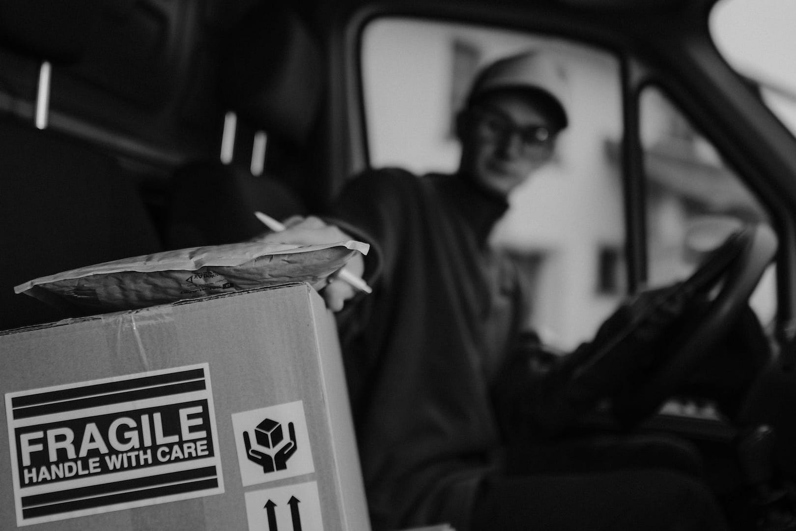 monochrome photo of man getting a parcel on top of carton box